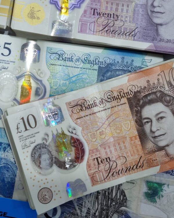 British banknotes in £5, £10, and £20 denominations scattered together. British banknotes in £5, £10, and £20 denominations scattered together.