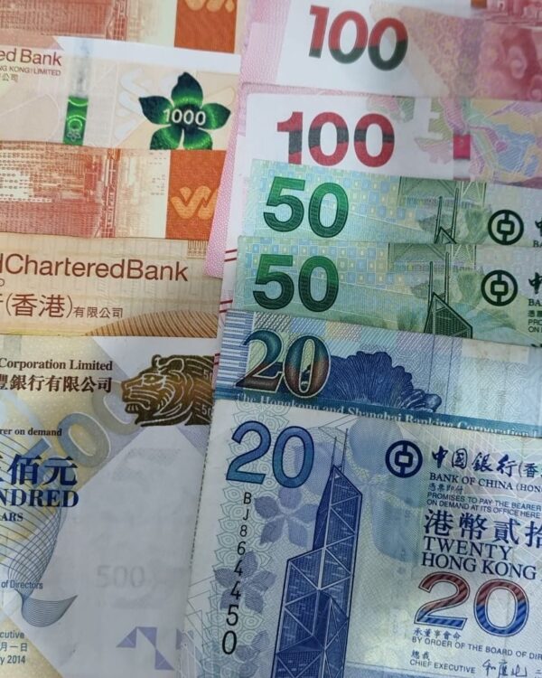 Mixed Hong Kong banknotes arranged on a Danesh Exchange no‑commission sign. Mixed Hong Kong banknotes arranged on a Danesh Exchange no‑commission sign.