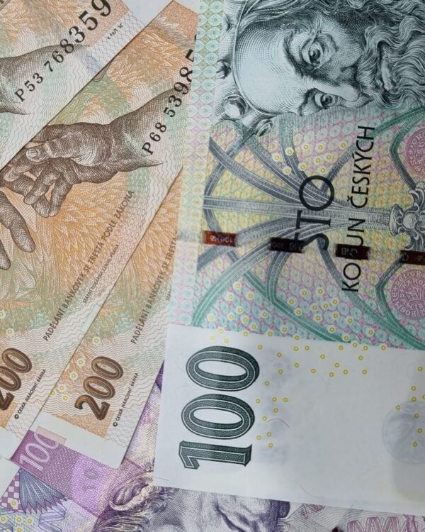 Czech koruna banknotes in 100, 200, and 1,000‑koruna denominations scattered on a surface. Czech koruna banknotes in 100, 200, and 1,000‑koruna denominations scattered on a surface.