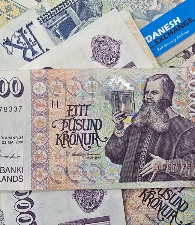 Icelandic banknotes, including a prominent 1,000‑króna note with a historical portrait, scattered among other colourful denominations with a small blue Danesh Exchange card. Icelandic banknotes, including a prominent 1,000‑króna note with a historical portrait, scattered among other colourful denominations with a small blue Danesh Exchange card.