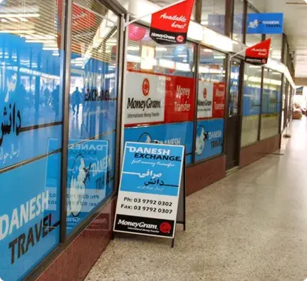 A Danesh Exchange storefront in a shopping corridor with blue signage and MoneyGram displays. A Danesh Exchange storefront in a shopping corridor with blue signage and MoneyGram displays.